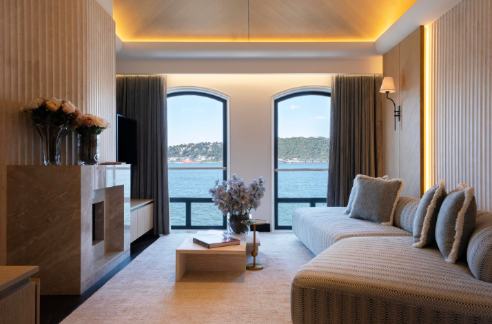 The seating area of a modern suite with arched windows overlooking the Bosphorus, featuring marble accents and soft-textured furniture for a sophisticated atmosphere.