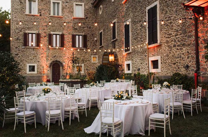 Restaurant Trippini’s outdoor courtyard with round tables, white chairs, and warm string lights.