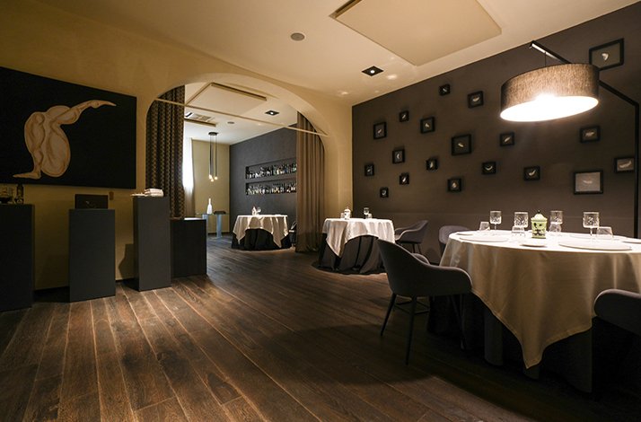 Elegant fine-dining room of restaurant L'Erba del Re with minimalist decor and softly lit tables.
