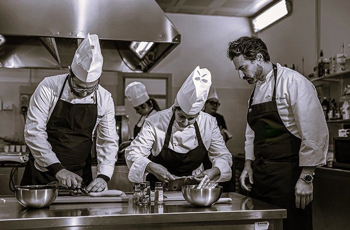 Chef Leonardo Fiorenzani supervising a team of chefs preparing food in the kitchen at La Sosta del Cavaliere.