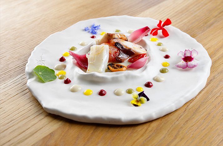 A refined presentation with edible flowers and small dots of sauce made at the La Capinera.