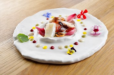 A refined presentation with edible flowers and small dots of sauce made at the La Capinera.