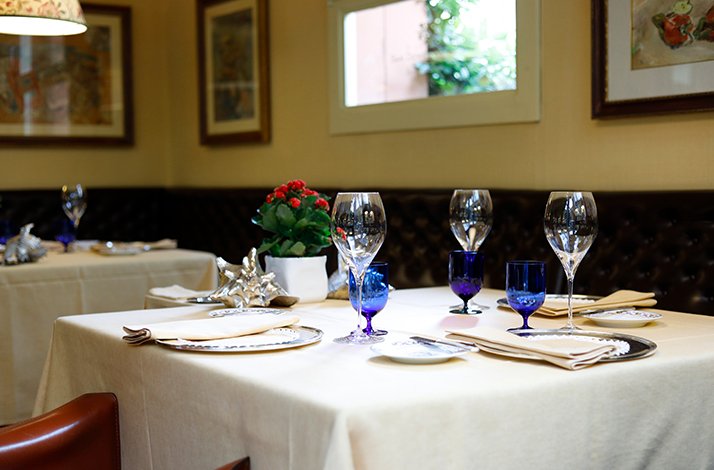 An elegantly set dining table with crystal wine and blue water glasses at Ristorante San Domenico.