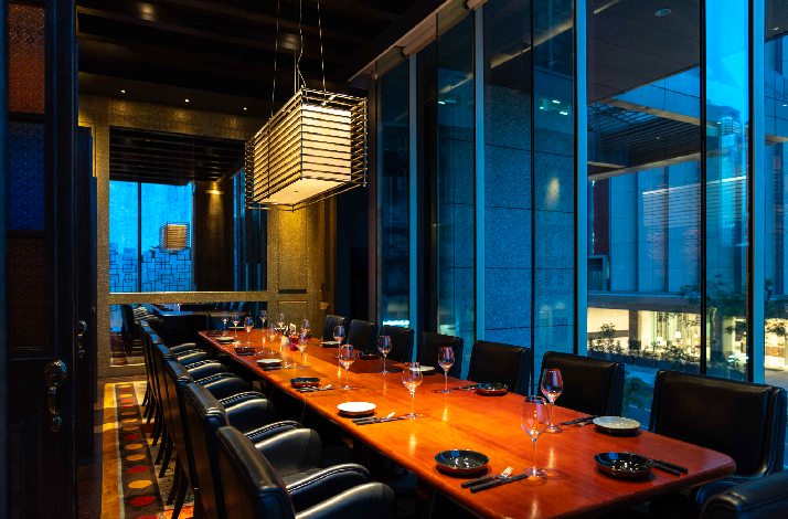 Modern long dining tables, featuring hanging lights and glass windows at The Cellar in Grand Hyatt Manila.
