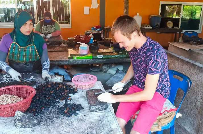 People processing cashew nuts by hand at a community workshop, with baskets of nuts and tools on the table.