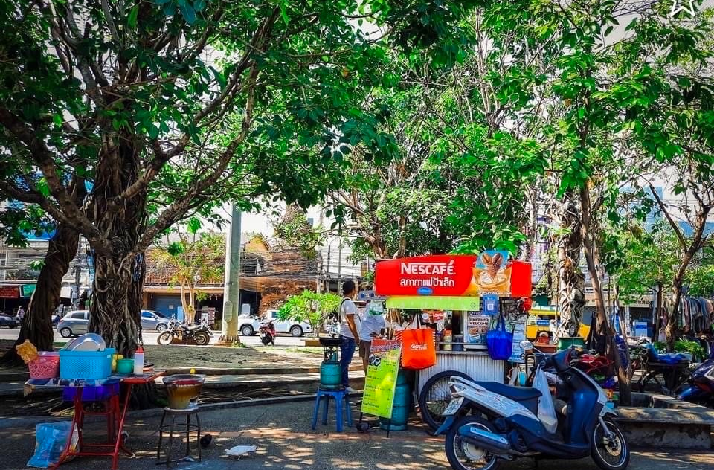 Street coffee stall under trees, motorbike parked, morning activity in Chiang Mai.