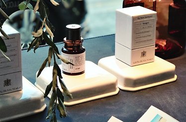 Naxos Apothecary perfumes and boxes with botanical sprig on illuminated display.