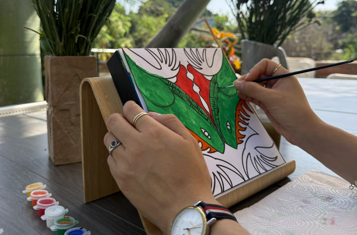 Participant painting a colorful Zapotec spirit animal design during an outdoor art workshop.