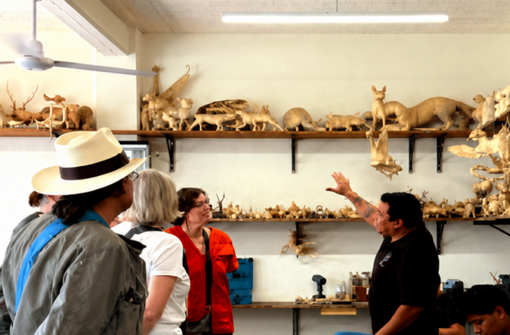Visitors observing handcrafted Zapotec wooden figures during a guided studio tour in San Martín Tilcajete.
