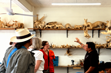 Visitors observing handcrafted Zapotec wooden figures during a guided studio tour in San Martín Tilcajete.