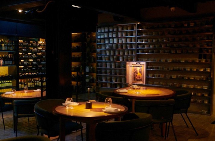 Candlelit dining room at El Chato in Chapinero Alto, Bogotá, with its wall of house-made preserves and open wine cellar