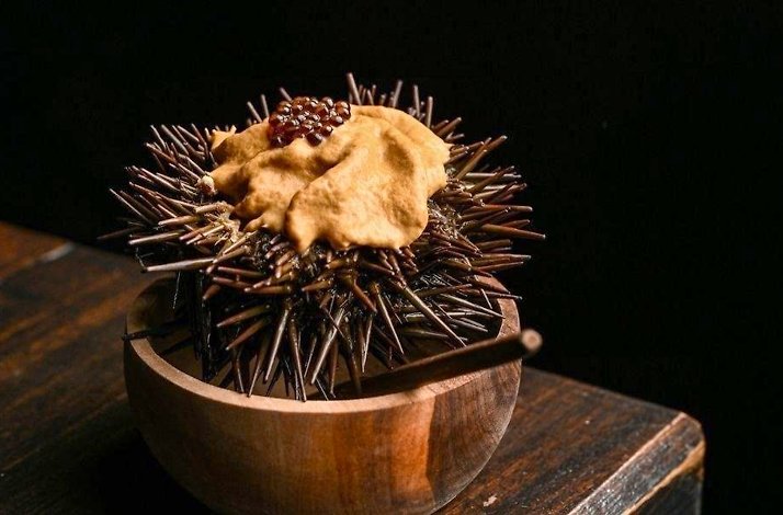 Sea urchin (erizo) served in its spiny shell on dark wood at Humo Negro, chef Jaime Torregrosa's live-fire Japanese izakaya in Bogotá