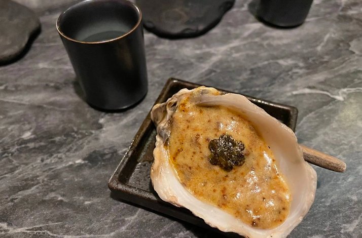 Ostras a la parrilla, the signature charcoal-grilled oyster with caviar, on the dark izakaya tabletop at Humo Negro, Bogotá