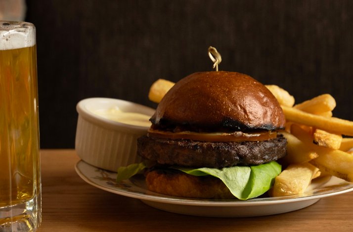 Hamburger paired with fried potatoes and a glass of beer served at Trudie's Tavern.