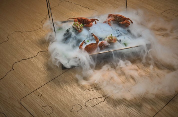 Artistic seafood dish with crabs presented on a tray surrounded by dramatic clouds of vapor, served at Michelin-starred LAB by Sergi Arola.