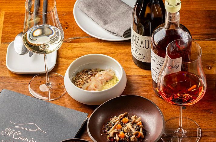A gourmet meal with wine and artisanal dishes served on a wooden table at El Camino Tapas Restaurant.