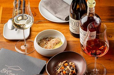 A gourmet meal with wine and artisanal dishes served on a wooden table at El Camino Tapas Restaurant.