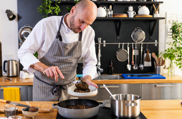Chef puts a portion of Dalmatian black risotto on a plate.