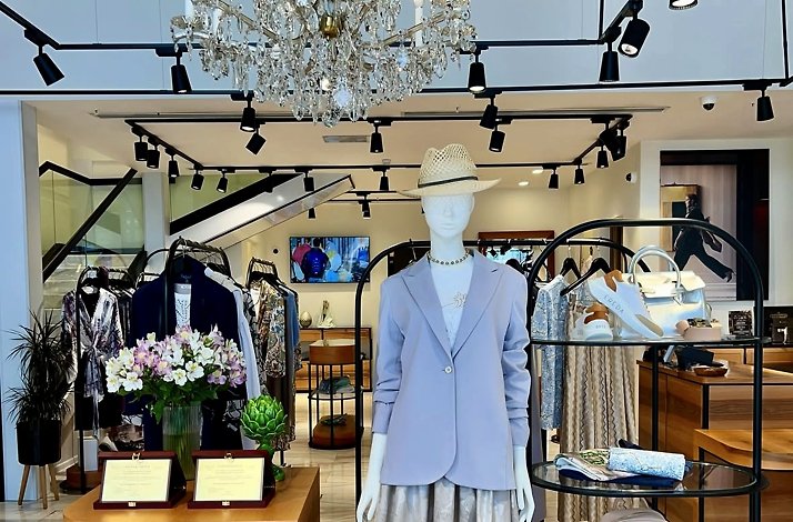 An elegant interior view of a mannequin wearing a light purple blazer and straw hat at the Cashmere and Silk boutique in Tashkent.