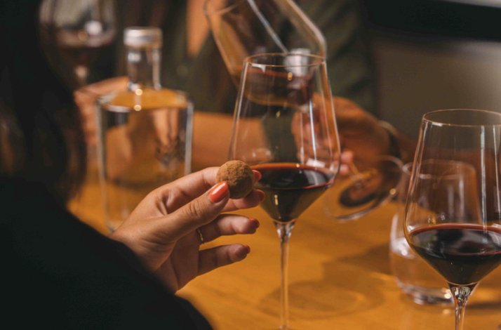  Guest pairing a chocolate truffle with red wine during a tasting experience at WOW Porto museum.