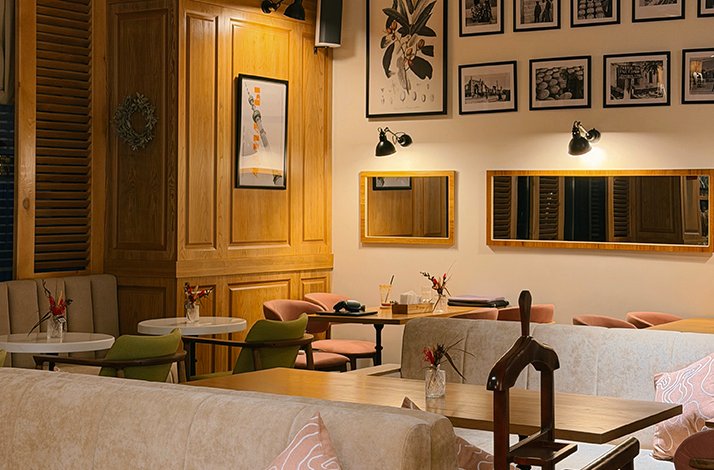 Cozy evening interior at Teplo Cafe, Tashkent, with warm wall lighting, framed artwork, mirrors, and colorful upholstered seating.