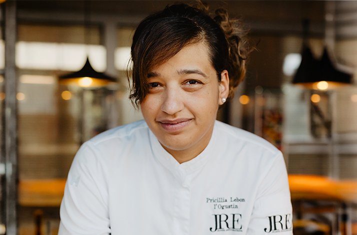 Chef Pricillia Lebon of L'Ogustin smiling in her white chef coat.
