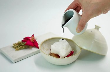 Chef pouring a dark sauce onto a foam-topped dish at Restaurant L'Ogustin.