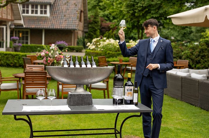 A sommelier inspecting wine in the garden terrace of Landhuishotel De Bloemenbeek in the Netherlands.