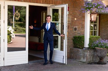A doorman welcoming guests at the entrance of Landhuishotel De Bloemenbeek in the Netherlands.