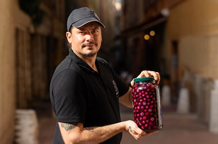 Chef Aurélien Martin holding jar of preserved berries in Nice Old Town.