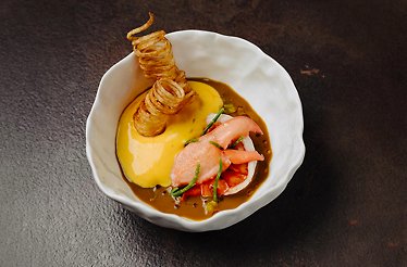 Elegant plated seafood dish with sauce and crisp garnish.