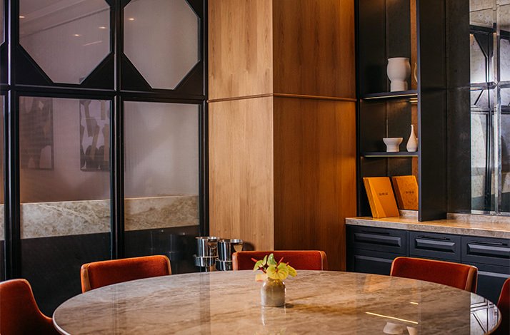The interior of Quirat restaurant in Barcelona, Spain, featuring modern, dark metal-framed glass dividers and warm wood paneling.