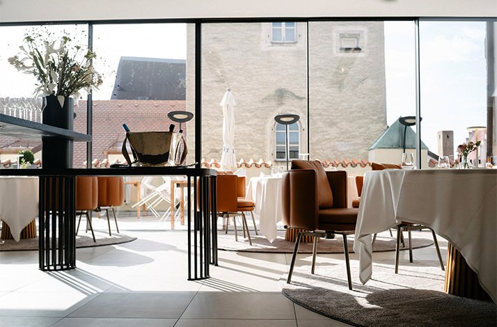 Dining room with modern leather chairs and large windows looking out at Storstad in Regensburg, Germany.
