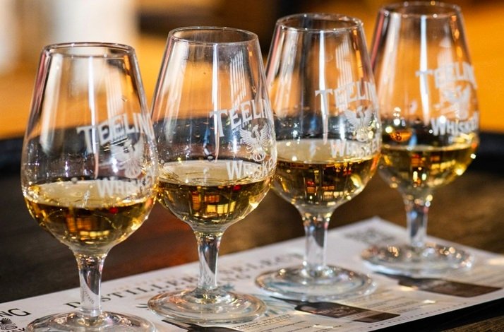 Four Teeling Whiskey tasting glasses filled with amber whiskey, lined up on a menu placemat.