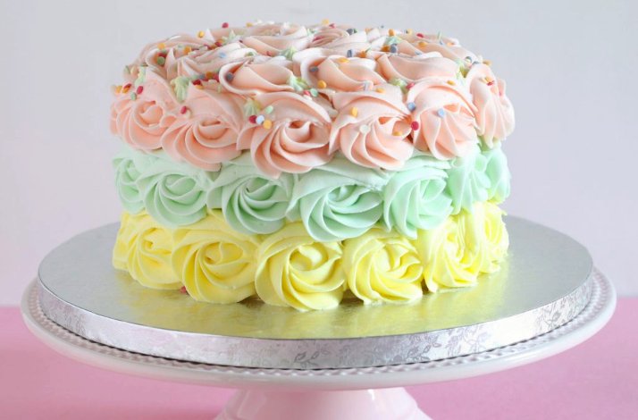 Cake with 3 layers of piping in yellow, green and pink buttercream frosting and sprinkled with edible elements