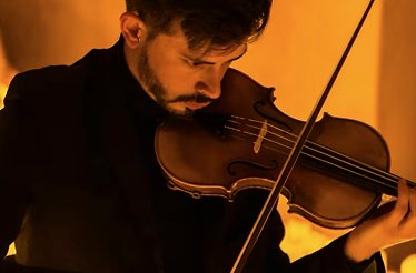 A violinist playing Vivaldi lighted by candles.