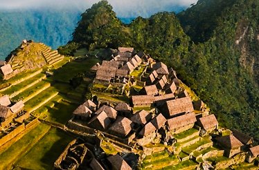 Aerial view of Machu Picchu's ancient Inca stone structures and terraced ruins nestled among misty Andean peaks.
