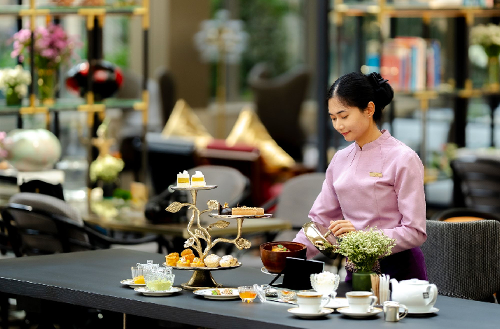 Afternoon tea service presented by staff in an upscale hotel setting.