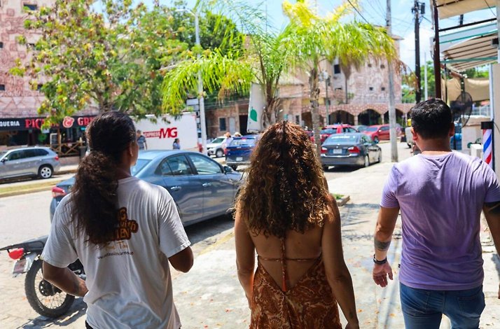 Visitors walking through a lively Cancun neighborhood with a guide, experiencing local streets, flavors, and authentic daily life on a food tour.