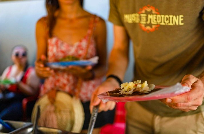 Traveler receiving a traditional Mexican street food sample during a Playa del Carmen culinary tour focused on local flavors and ancestral ingredients.