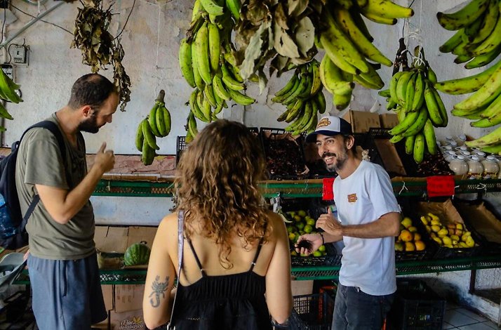 Visitors exploring a vibrant Cancun market with a guide, surrounded by fresh produce on a cultural food tour experience.