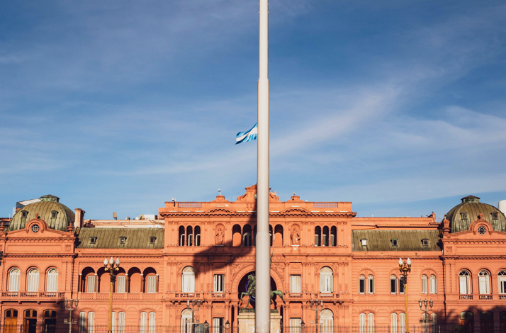 Argentine flag waving above Casa Rosada, symbolizing national identity and history in Buenos Aires.