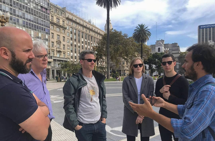 Small group walking tour in Buenos Aires with an expert guide sharing historical insights in a city plaza.