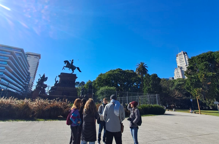 Small group gathered near an equestrian monument in Buenos Aires as a guide shares historical context and sparks discussion.