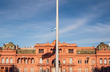Argentine flag waving above Casa Rosada, symbolizing national identity and history in Buenos Aires.