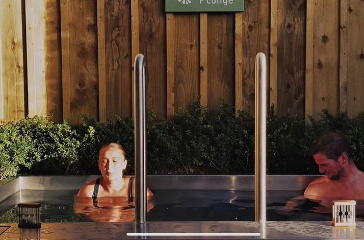 Two people relaxing in an outdoor tub at the Treehouse Sauna.