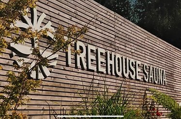 Treehouse Sauna logo on a wooden fence.