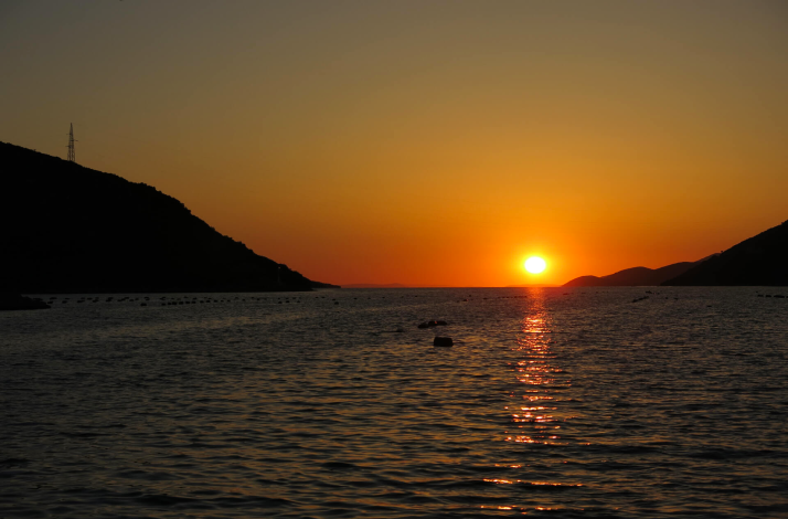 Sunset glowing over oyster beds and silhouetted hills in the Bay of Mali Ston, Pelješac peninsula, Croatia.