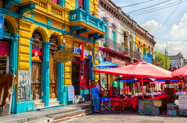 Vibrant La Boca street with historic façades, flags, and open-air cafés along Caminito.