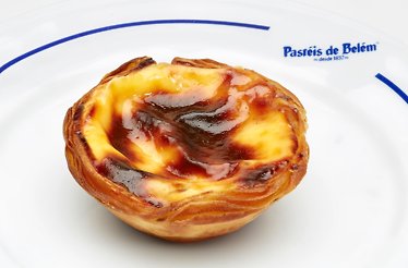 Close-up of Portuguese pastry served on a white Pastéis de Belém glass plate.